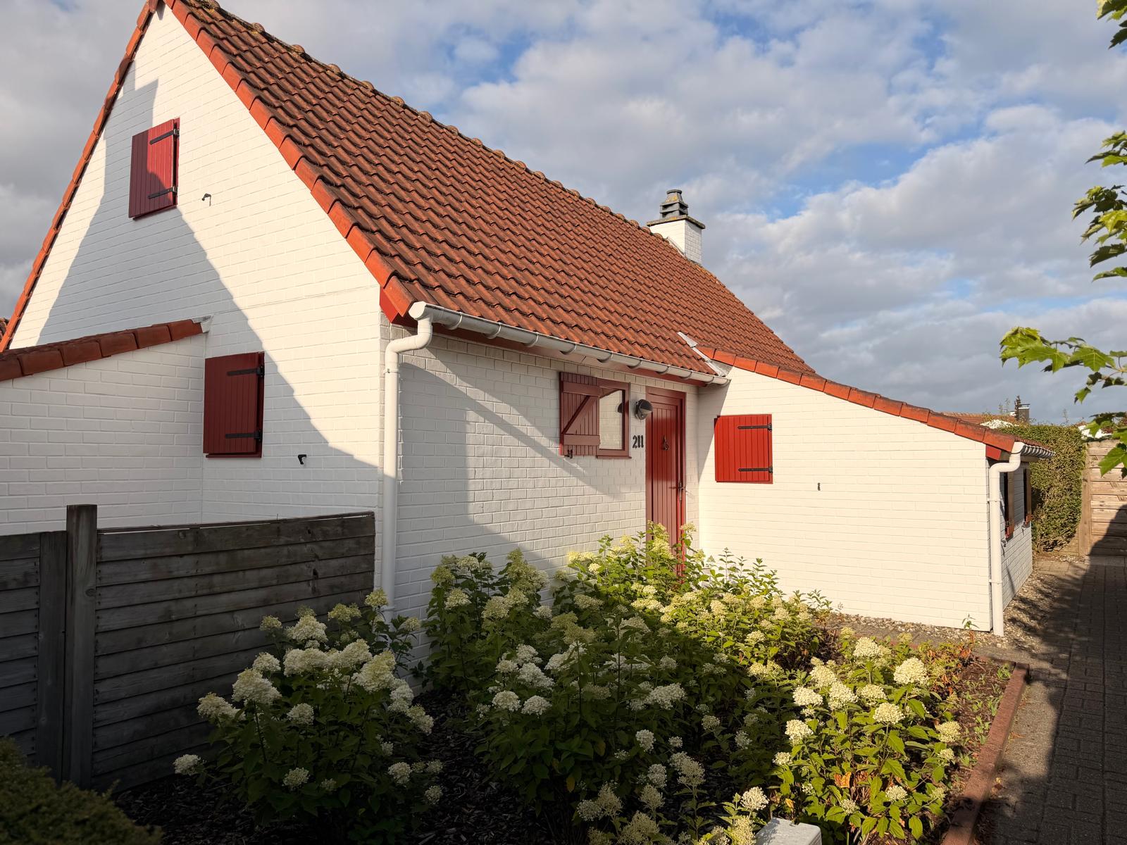 Front of NordHuys holiday home with its red door and shutters